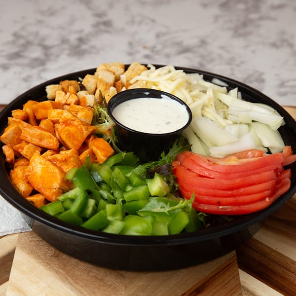 A salad with buffalo chicken, green peppers, tomatoes, cheese, croutons, and ranch dressing.